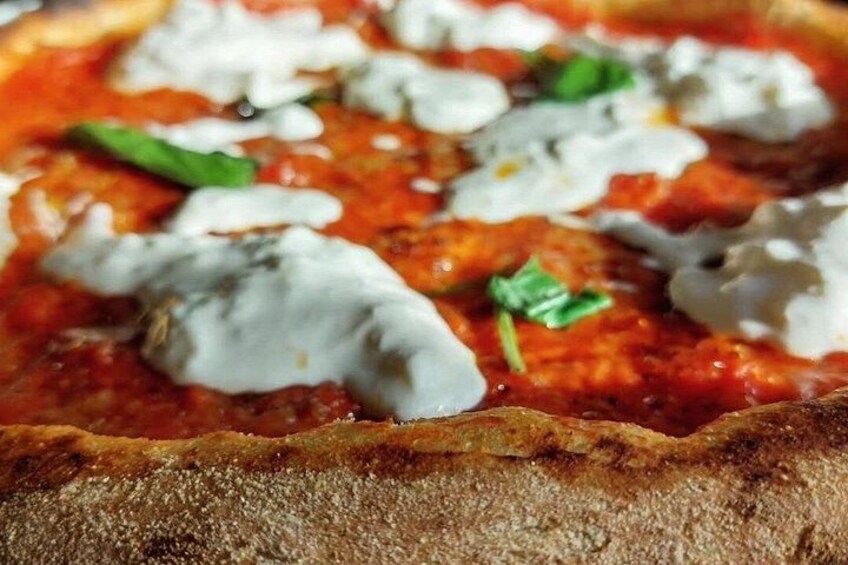 En närbild på en pizza med tomatsås, ost och basilika. 1