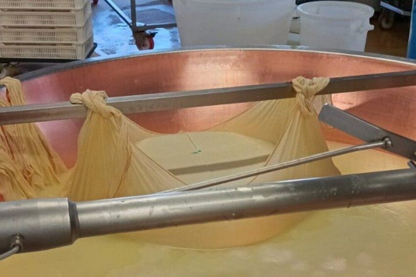 A copper vat with a yellow liquid, a metal rod, and a cloth. 2