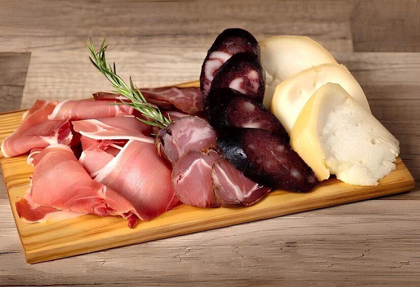 A wooden cutting board with various cured meats and cheese. 4