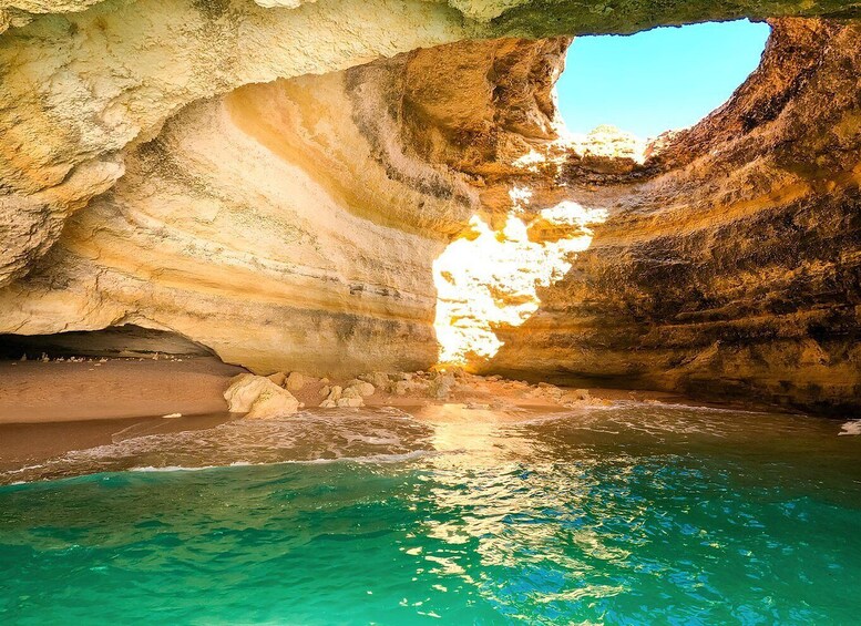 A cave with a pool of clear water and sunlight streaming through an opening. 5