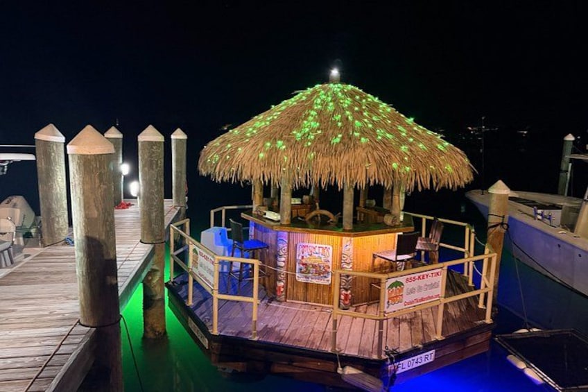 Ein an einem Steg festgemachtes Boot mit einem strohgedeckten Gebäude, einem Holzboden und einem Schild. 2