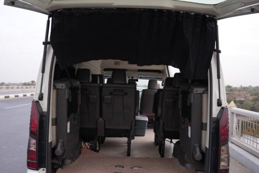 The back of a white van with an open cargo area, two black seats, and a black tarp covering the rear. 5