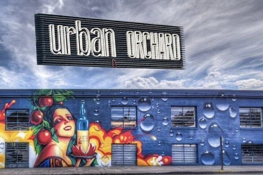 A building with a mural of fruits and vegetables, a sign reading 'Urban Orchard,' and water droplets on the wall. 4