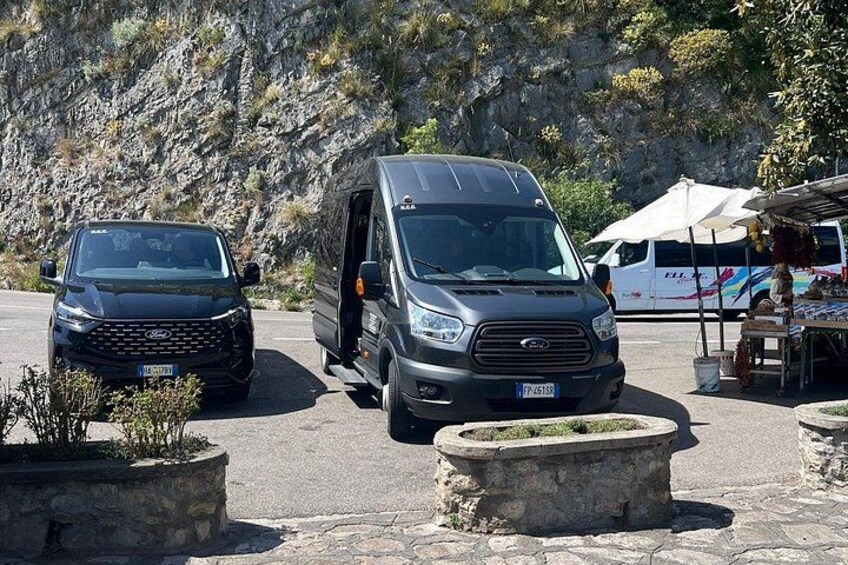 Due furgoni parcheggiati su una strada con terreno roccioso e una tenda bianca sullo sfondo. 2