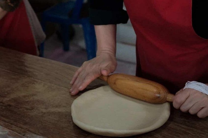 Eine Person knetet Teig auf einer Holztischplatte. 5