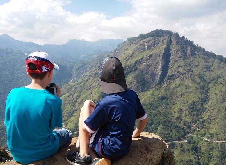 Two people sitting on a rock overlooking a mountainous landscape. 3