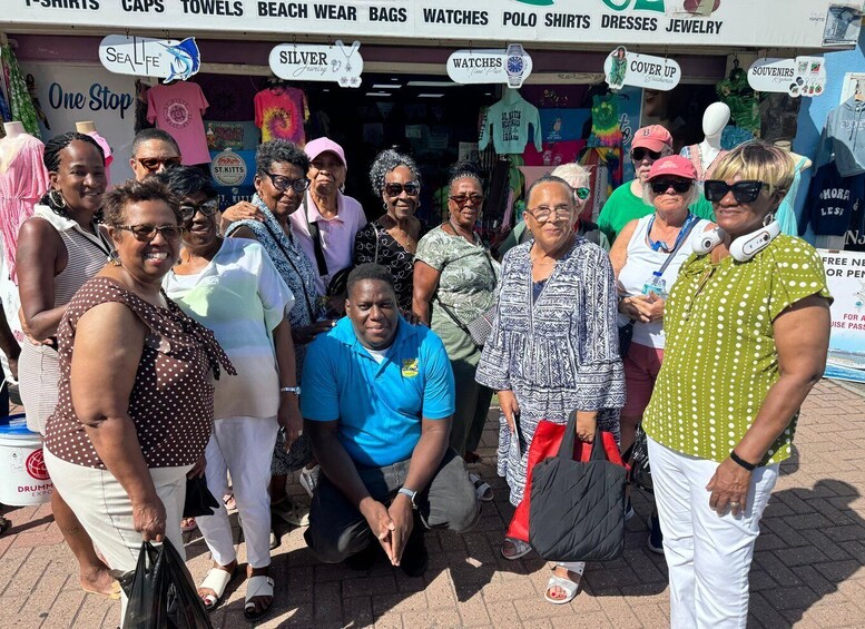 A group of people in front of a store with signs advertising various items like T-shirts, caps, towels, beach wear, bags, watches, polo shirts, dresses, and jewelry. 2