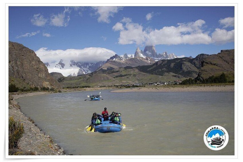 Un río con una balsa y un bote, rodeado de montañas y un cielo despejado. 3