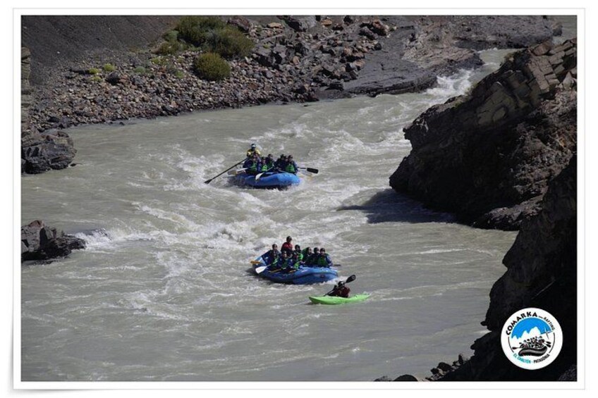 Dos equipos de rafting en aguas bravas remando por un río con orillas rocosas. 2