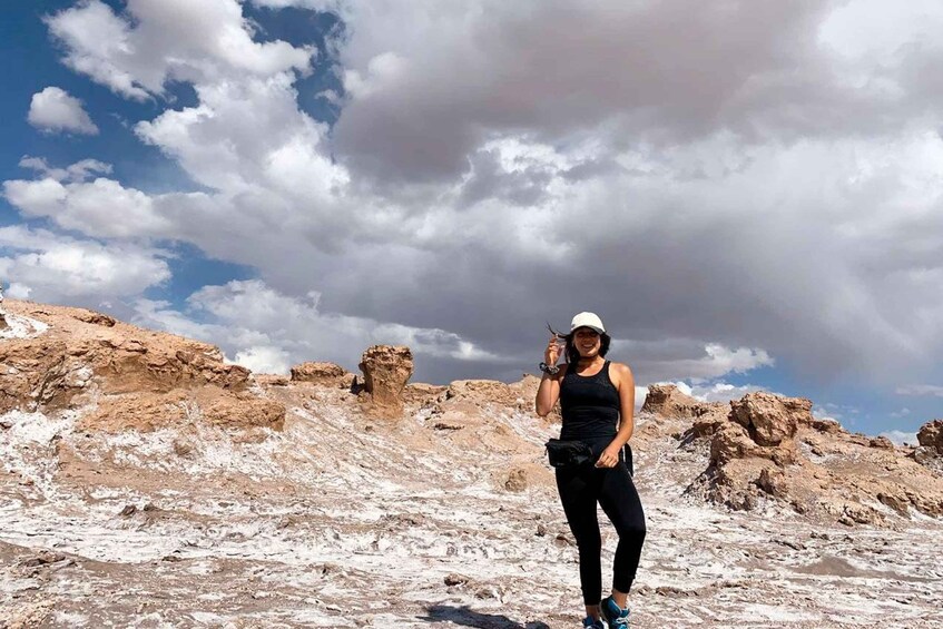 A person standing on a rocky terrain with sparse vegetation, under a partly cloudy sky. 1