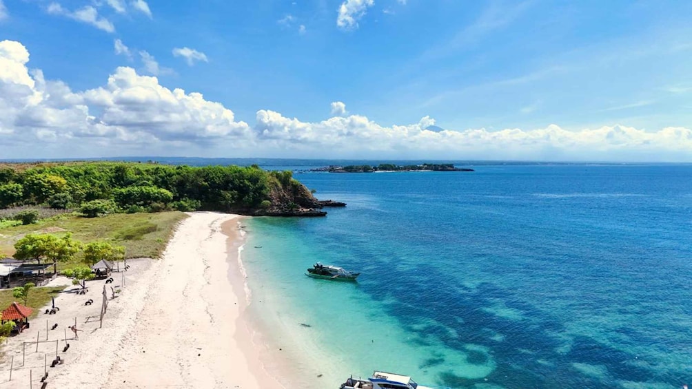 A beach with clear turquoise waters, a sandy shore, and a small boat anchored near the shore. 5