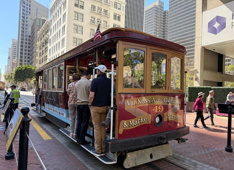 A vintage streetcar at a station with passengers boarding. 1