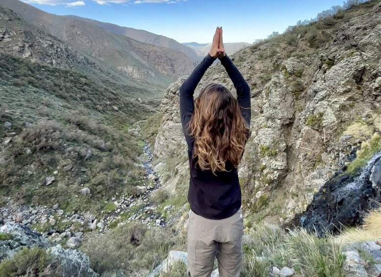 A person standing with arms raised in a mountainous landscape. 1