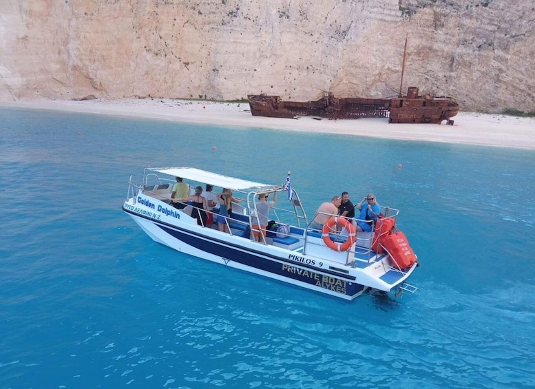A boat named 'Golden Dolphin' with passengers, near a rocky coastline. 5
