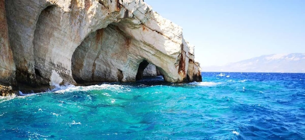 A coastal rock formation with a natural arch and turquoise waters. 1