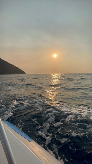 A boat on a body of water with the sun reflecting off the surface. 2
