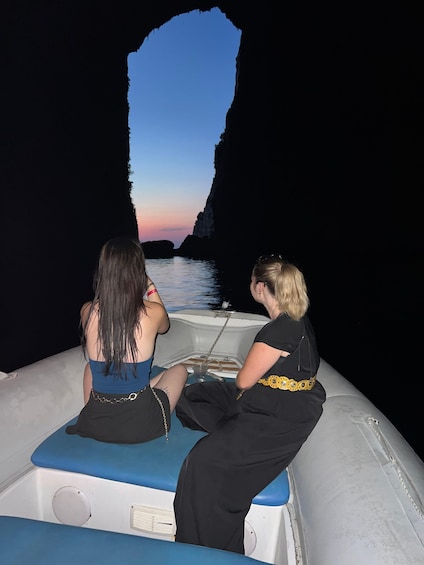 Two people on a boat with a rocky coastline in the background. 3