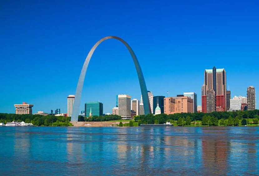A city skyline with a prominent arch structure, various buildings, and a body of water reflecting the cityscape. 5