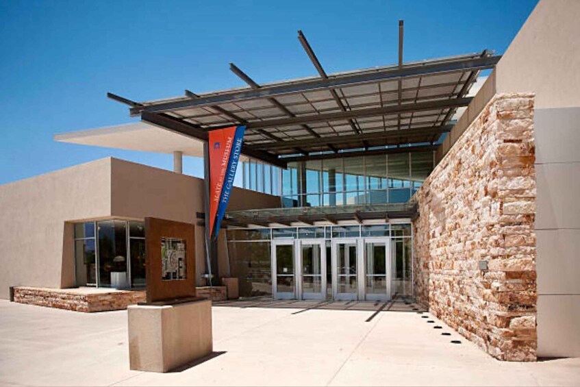 A modern building with a glass entrance, stone walls, and a blue banner. 5