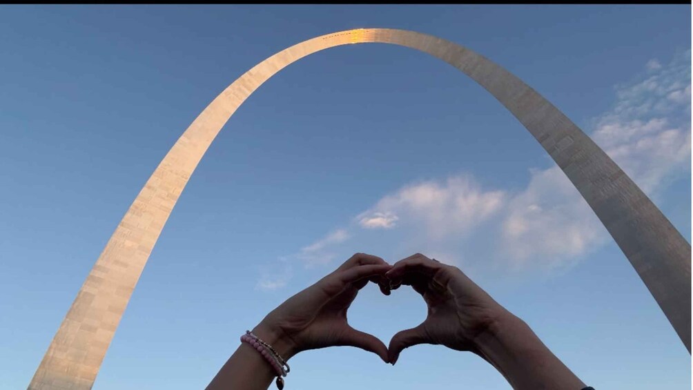 A heart-shaped gesture framed by the Gateway Arch against a clear sky. 4