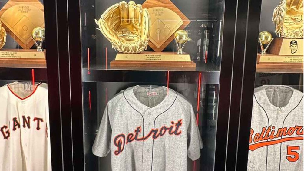 A display case with baseball memorabilia including jerseys and trophies. 2