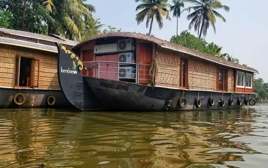 A houseboat named 'Kera Kerala' on water with palm trees in the background. 3