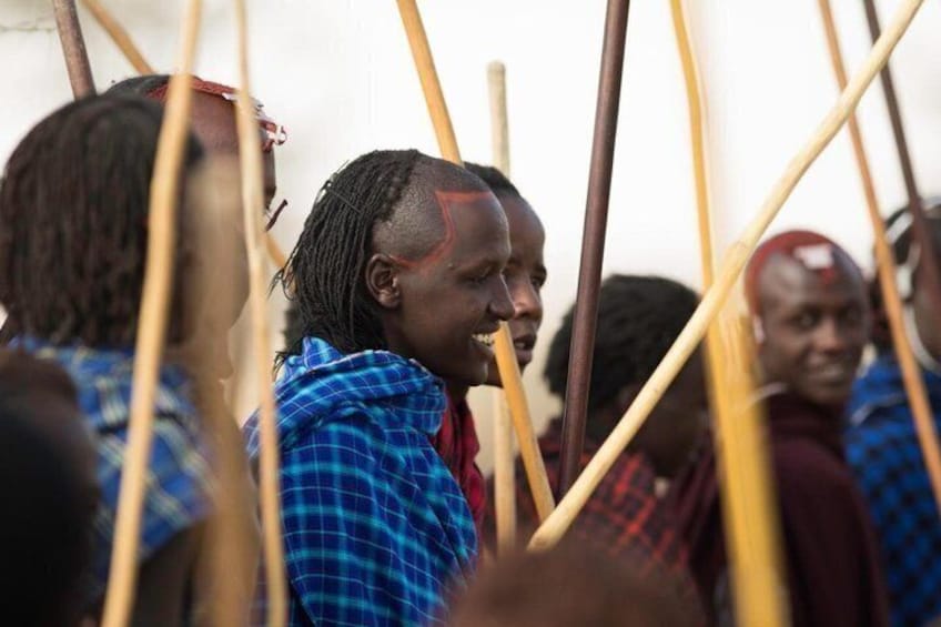 A group of people in traditional attire holding long wooden sticks, possibly participating in a cultural or ceremonial event. 4