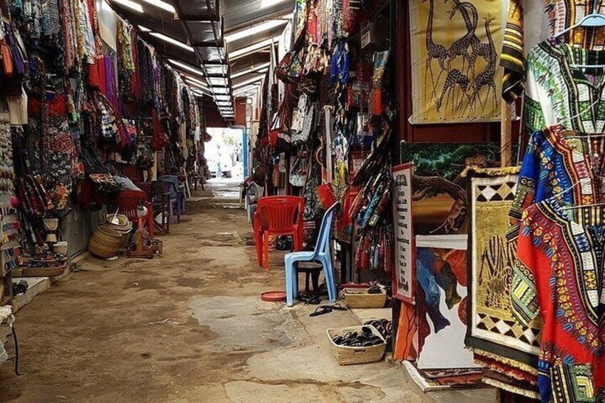 A narrow market aisle with colorful textiles and handicrafts on display. 3
