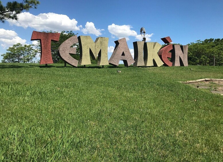 Large letters spelling 'TEMAIKEN' on a grassy hill with trees in the background. 5