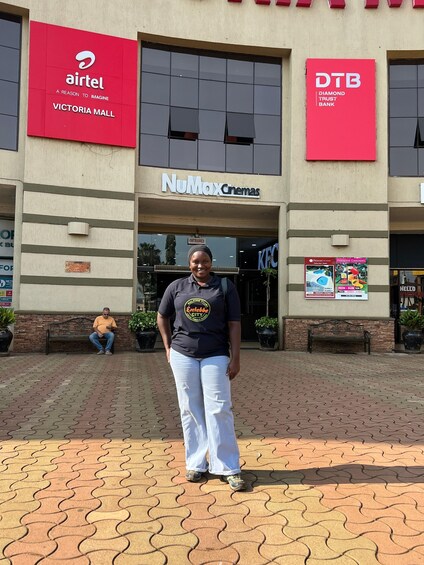 A woman standing in front of Victoria Mall with banners for Airtel, DTH, and NuMax Cinemas. 2