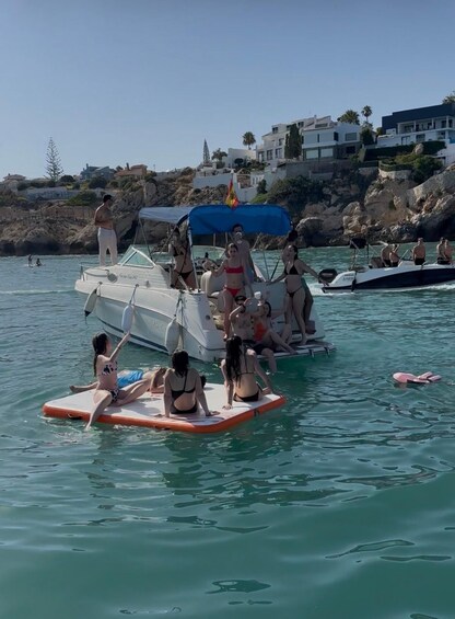 People on a boat and on floating platforms in a body of water with buildings in the background. 2