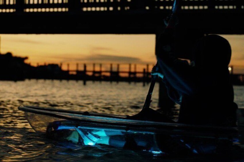 Een boot met iemand erop, een brug op de achtergrond en een zonsondergang boven het water. 3