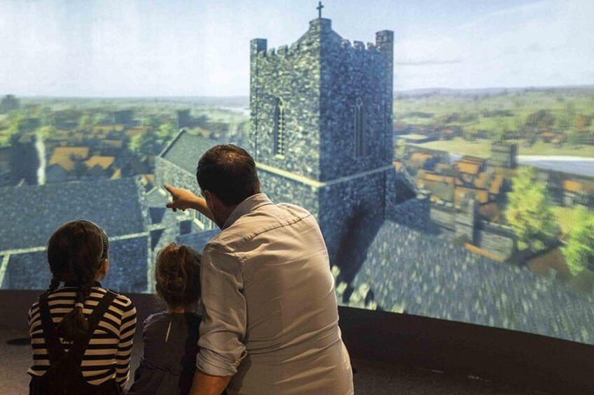 A man pointing at a castle-like structure with a view of a town below. 4
