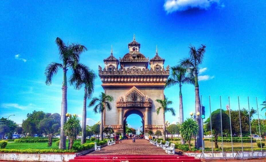 A large, ornate archway with three towers, surrounded by palm trees and a paved walkway. 1