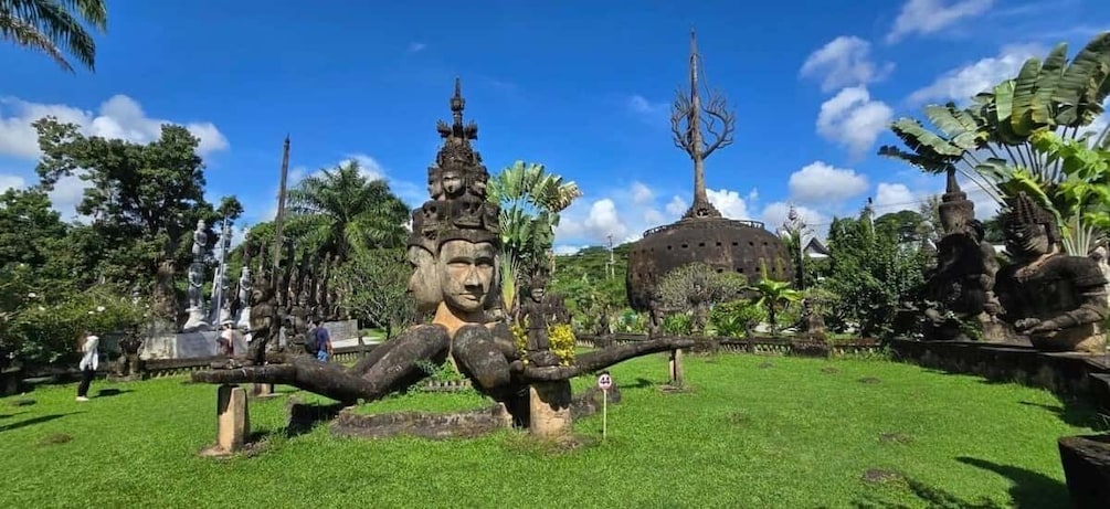 A large Buddha statue in a lush garden with a temple in the background. 4