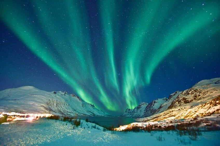A snowy landscape with a lake and mountains under a night sky with green aurora borealis. 2