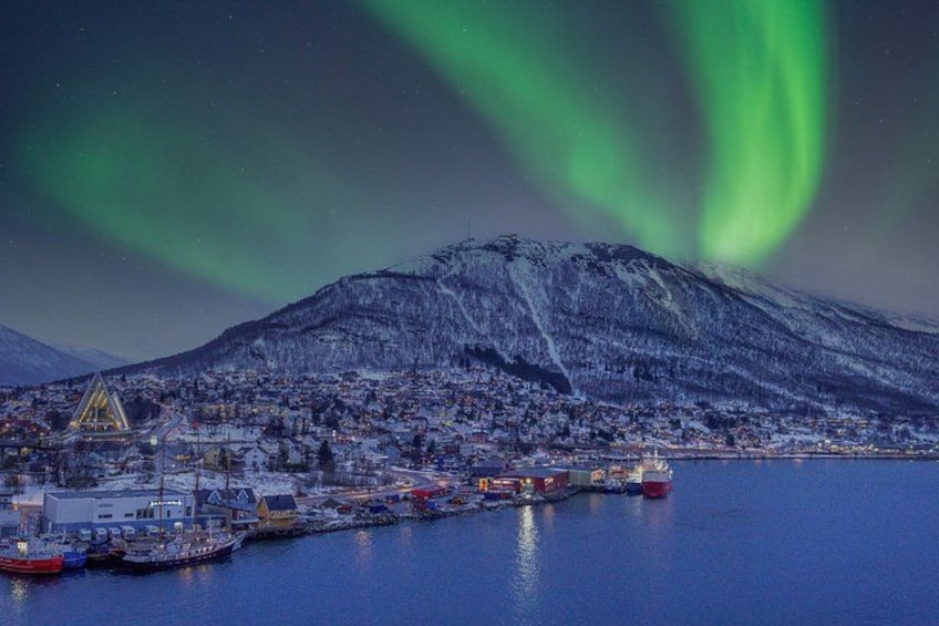 A snowy mountain, a town, and the northern lights. 2