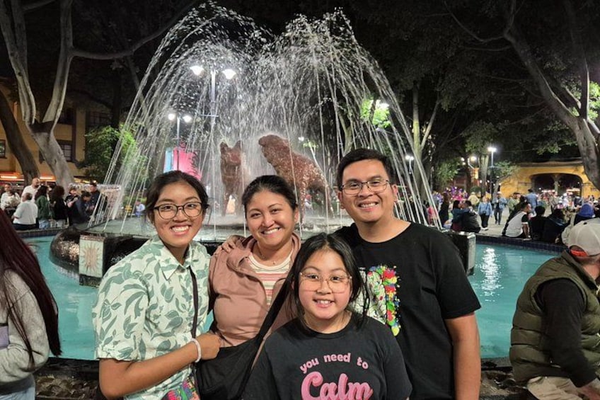 A group of people posing in front of a fountain with water jets. 2