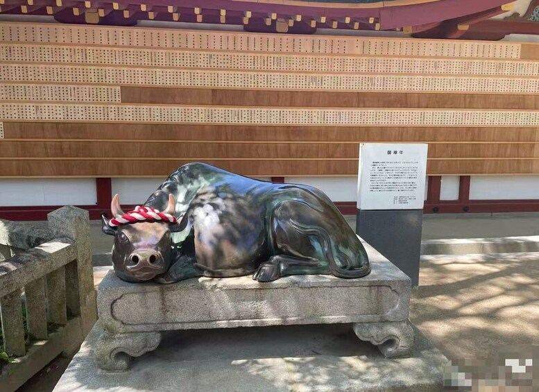 A statue of a bull with a red and white rope on its head, placed on a stone platform. 3