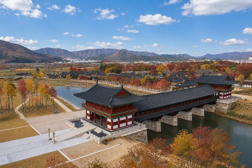 A traditional building with a red and white facade, a stone bridge, and a river. 3
