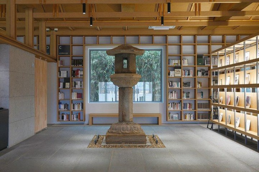 A traditional Japanese library with wooden bookshelves, a central stone lantern, and a large window. 5