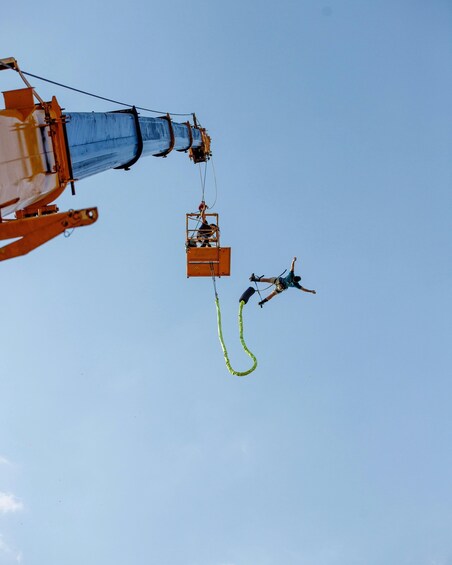 A bungee jumping activity with a person suspended by a harness and a safety harness attached to a crane. 2