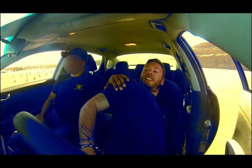 Two people in a car with a desert landscape in the background. 4