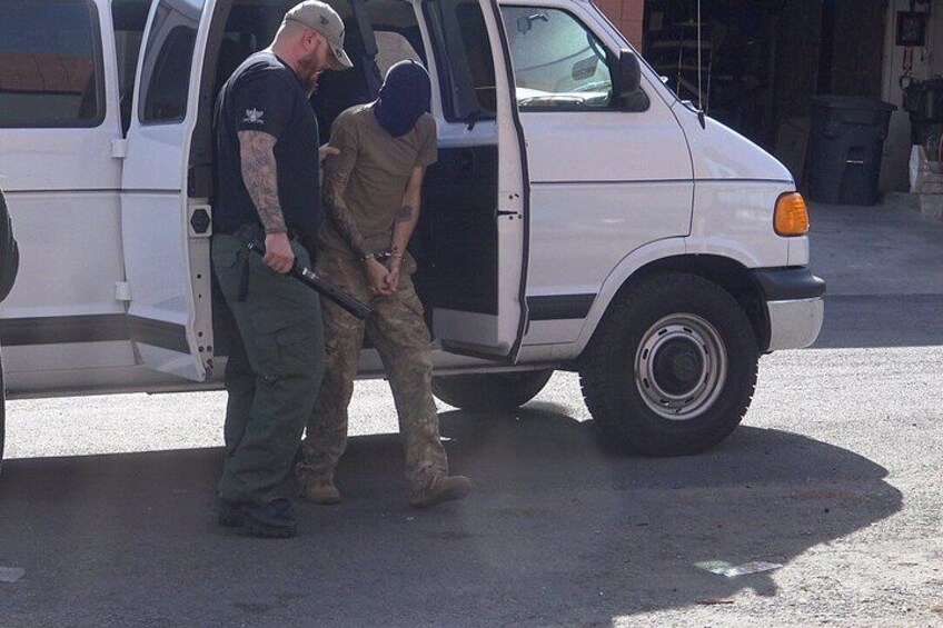 A white van parked on a street with two individuals standing beside it. 2