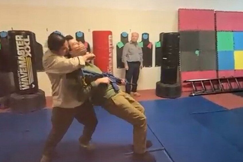A martial arts training session with a person performing a throw on a training dummy. 5