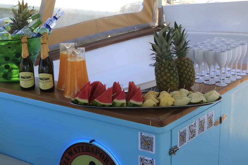 A bar with a tropical theme, featuring bottles of wine, a pitcher of beer, and a variety of fruits and ice cubes. 4
