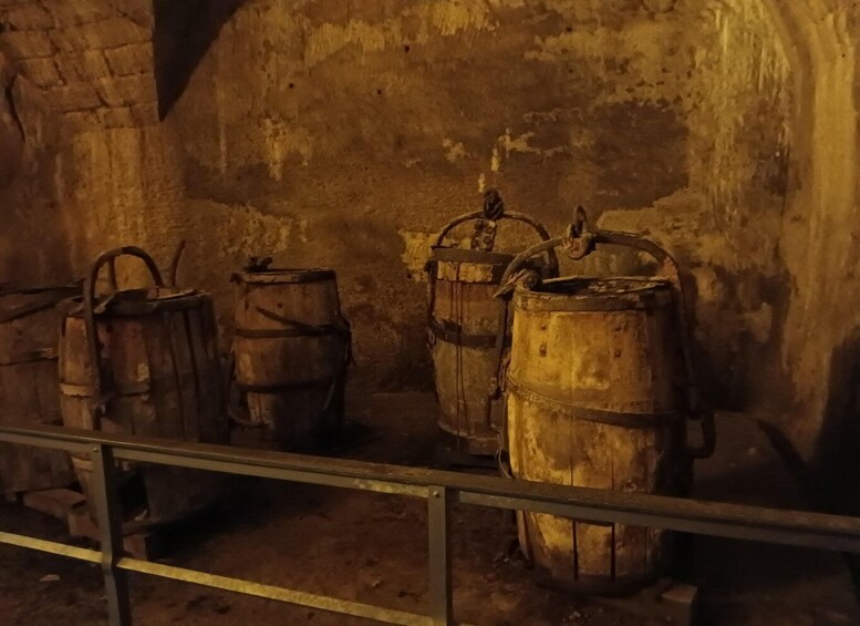 Three wooden barrels in a dimly lit room with a brick wall. 4