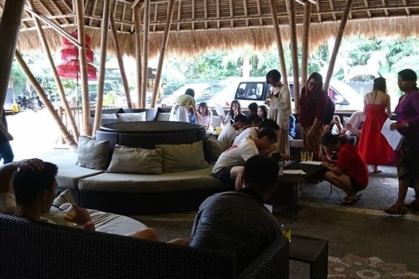 Un área de estar al aire libre con techo de paja, un sofá y una mesa de comedor. 5