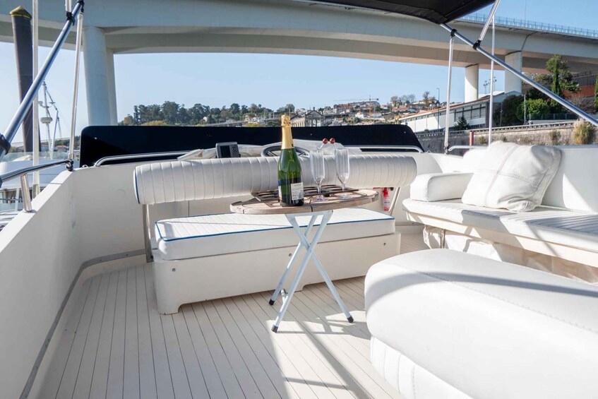 A boat deck with a white cushioned seating area, a bottle of champagne, and glasses on a tray. 5