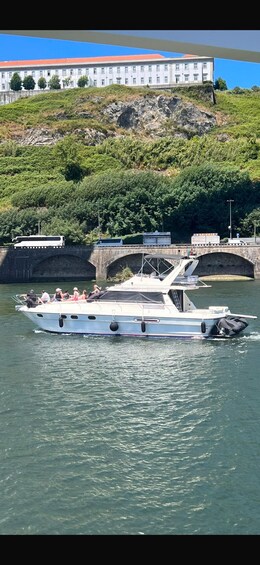 A white boat with passengers on a river, a bridge, and a building in the background. 4
